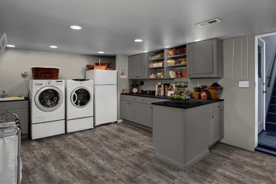 vinyl plank flooring in laundry room in downstairs kitchen with gray cabinetry